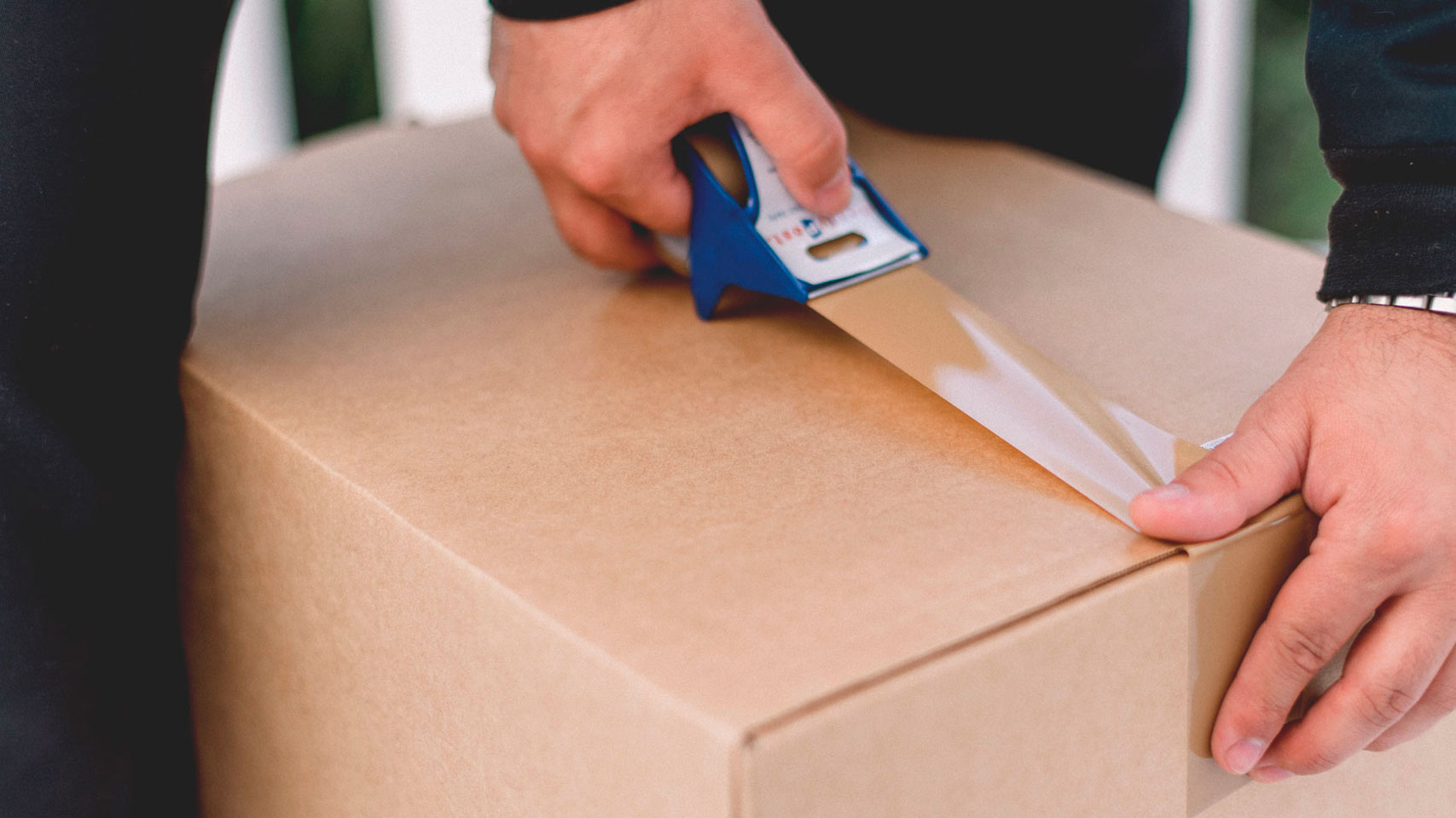 Bellotto Trasporti - Operatore chiude uno scatolone con nastro da pacchi, per un trasloco sicuro e organizzato